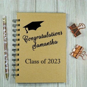 May include: A brown spiral bound notebook with the text "Congratulations Samantha Class of 2023" and a black graduation cap graphic.