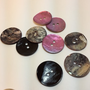 May include: Assortment of 10 two-hole buttons in various colors and patterns, including black, brown, pink, and white. The buttons are made of a smooth, shiny material.