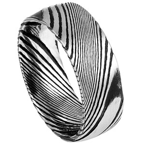 Pode incluir: Um anel de prata com um design único e espiral. O padrão é composto por linhas finas pretas que criam um efeito ondulado.