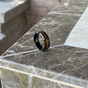 May include: A black and brown wood ring with a polished finish.
