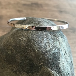Puede incluir: Un brazalete de plata martillado. El brazalete es simple y elegante, con un acabado liso y pulido.