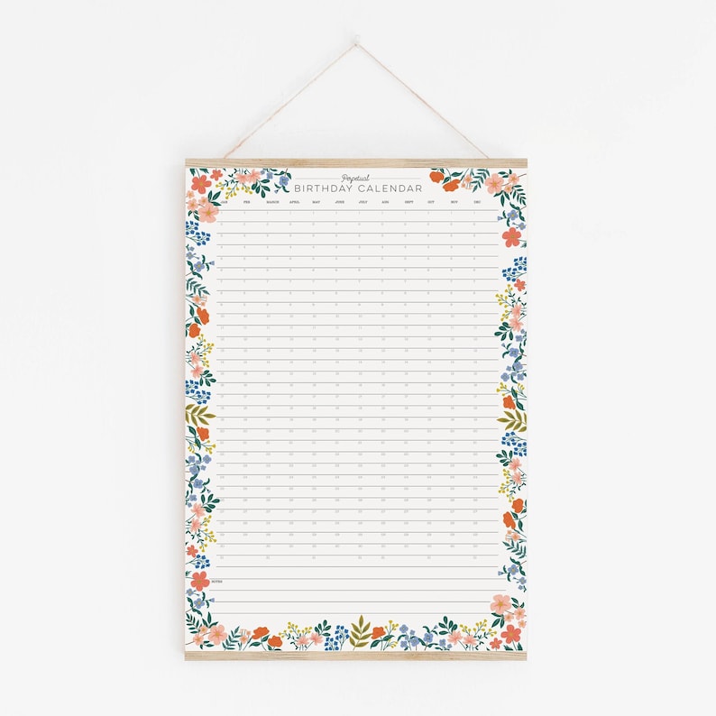 May include: A white floral birthday calendar with a wooden dowel at the top. The calendar has a floral border with pink, orange, and blue flowers. The calendar is labeled "Birthday Calendar" at the top.
