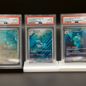 May include: Three Pokemon trading cards in protective cases. The cards are graded Gem Mint 10 and feature Squirtle, Wartortle, and Blastoise ex. The cards are from the 2023 Pokemon Mew En set.