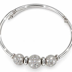 May include: A silver-toned bypass bangle bracelet featuring three spherical beads. The central bead is larger than the two flanking beads, and all three are encrusted with small, clear, reflective stones that create a sparkling, textured appearance.