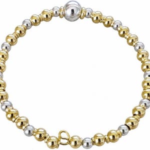 May include: A gold and silver beaded bracelet. The bracelet features alternating gold and silver beads, with a larger silver bead at the center. The bracelet has a small gold charm with a cursive letter "S".