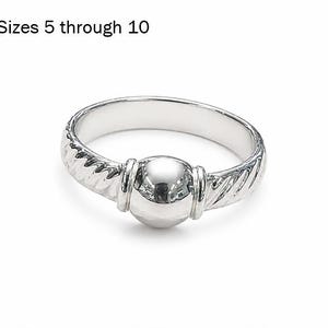 May include: A silver-toned ring featuring a central smooth spherical bead flanked by two vertical bands, with a twisted rope-like texture along the rest of the band. The text "Sizes 5 through 10" is printed in black above the ring on a white background.
