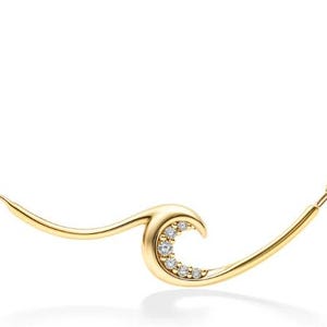 May include: A gold-colored necklace featuring a wave design. The wave is embellished with small, clear gemstones. The necklace has a delicate chain and a polished finish, suitable for everyday wear or special occasions.