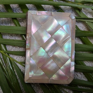 May include: A small, rectangular box with a decorative, iridescent mother-of-pearl inlay. The inlay is arranged in a diamond pattern and has a subtle shimmer.