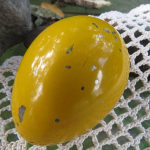 Pu&ograve; includere: Un uovo giallo con una finitura lucida e lucida. L'uovo presenta diverse piccole macchie argentate sulla sua superficie.