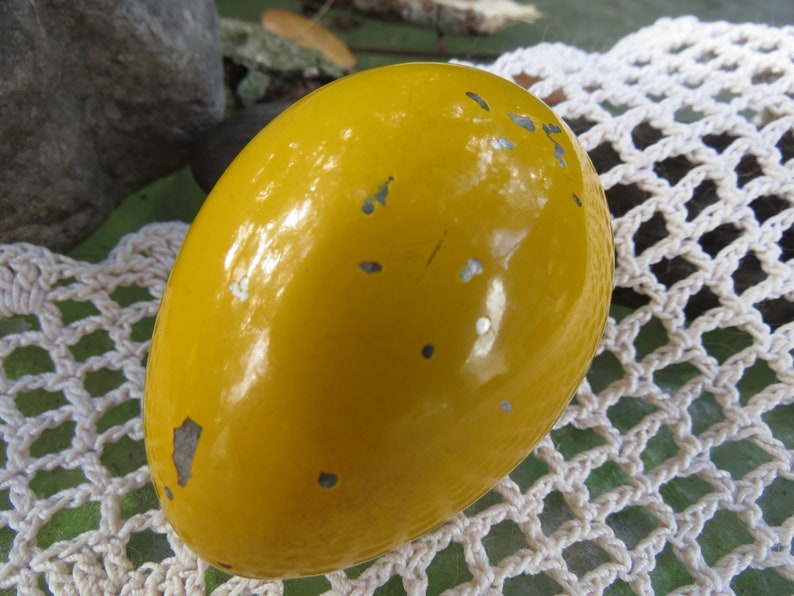 Pu&ograve; includere: Un uovo giallo con una finitura lucida e lucida. L'uovo presenta diverse piccole macchie argentate sulla sua superficie.