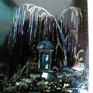Pu&ograve; includere: Una scatola laccata nera con una scena di un pagoda e alberi intarsiati con madreperla iridescente. La scena &egrave; delineata con vernice dorata.