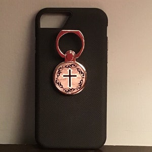 May include: A black phone case with a gold ring holder featuring a cross design.