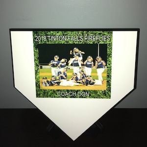 May include: A white and black baseball home plate plaque with a green grass border. The plaque features a photo of a youth baseball team with the text "2018 Tinton Falls Fireflies" and "Coach Don".