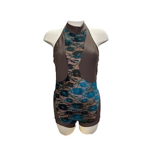 以下が含まれることがあります： フロントにシアーレースパネルが付いたブラウンの halter スタイルレオタード。レースはブラックでターコイズのアクセントが施されています。