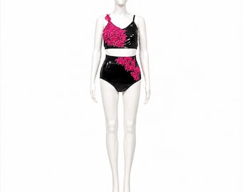 Puede incluir: Un conjunto de traje de baño de dos piezas en tela negra brillante con adornos florales de color rosa intenso. La parte superior tiene un tirante grueso y uno fino, mientras que la braga de talle alto presenta detalles florales rosas a juego.