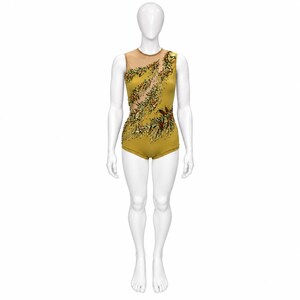 May include: A sleeveless mustard yellow leotard featuring a sheer mesh panel across the upper chest and shoulder. The garment is decorated with an asymmetrical pattern of green, gold, and brown sequins and beads arranged in leaf-like motifs.