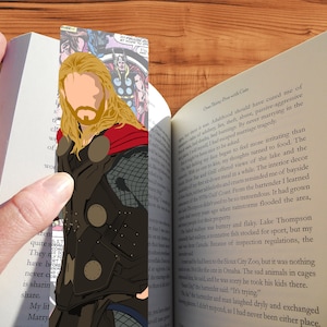 May include: A bookmark featuring a cartoon illustration of Thor, a superhero from Marvel Comics. The bookmark is made of durable, high-quality materials and is perfect for any fan of the Marvel Universe.