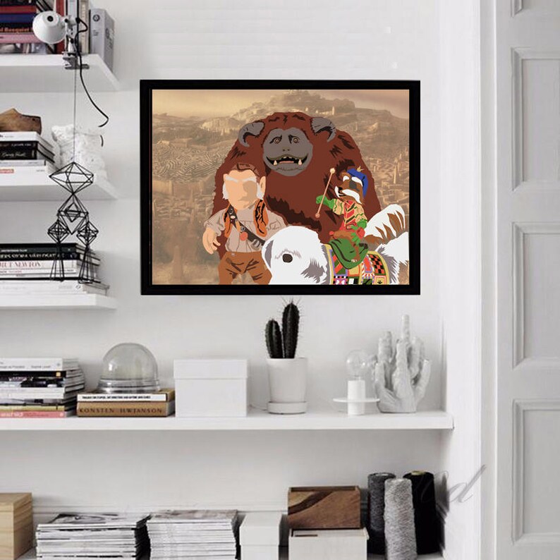 May include: A framed print of a cartoon illustration featuring a brown furry creature with a white face, a human-like figure wearing a brown shirt and pants, and a small figure riding a white creature. The background is a cityscape.