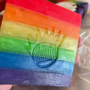 May include: A bar of soap with a rainbow design and a stylised graphic of a creature with a crown.