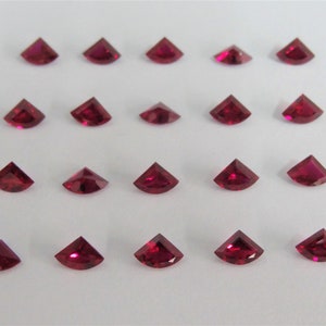 Può includere: Venti pietre preziose di colore rosso rubino a forma triangolare, disposte in quattro file di cinque pietre ciascuna.