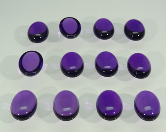 May include: Twelve oval-shaped, deep purple cabochon gemstones arranged in three rows of four. Each stone features a smooth, polished, domed surface with a translucent quality, reflecting light across the rounded tops of the dark violet gems.