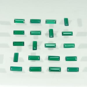 Pode incluir: Uma coleção de vinte pequenas pedras preciosas retangulares verdes dispostas em um padrão de grade. Cada pedra apresenta uma superfície lisa e polida com um tom verde esmeralda consistente e bordas afiadas, refletindo a luz uniformemente.