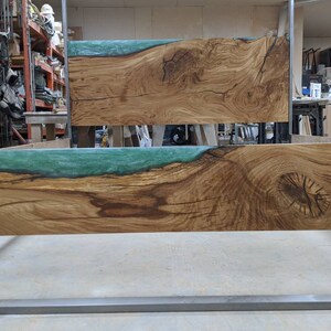 May include: A wooden headboard with a large knot and a green epoxy resin inlay. The headboard is made of natural wood with a rustic finish.