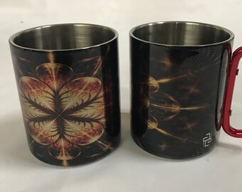 May include: Two stainless steel travel mugs with a black and gold abstract design. One mug has a red carabiner handle.