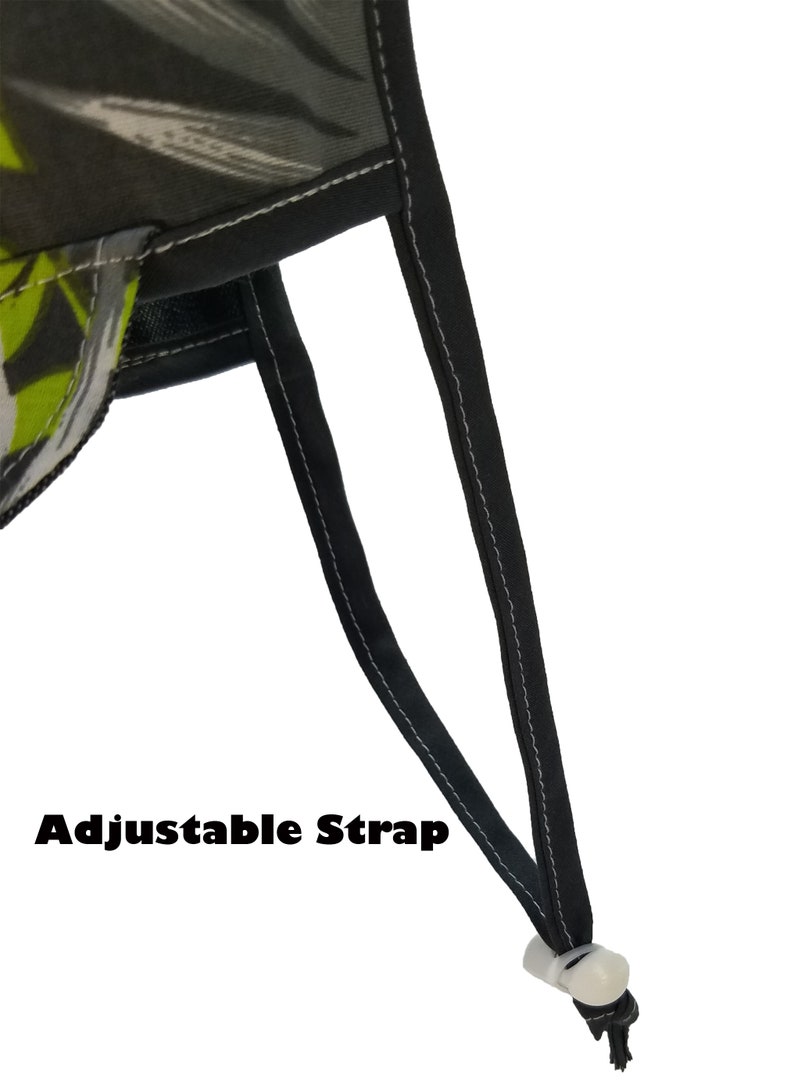 May include: Close-up of a black adjustable strap with a white plastic buckle. The strap is attached to a green and black patterned fabric.