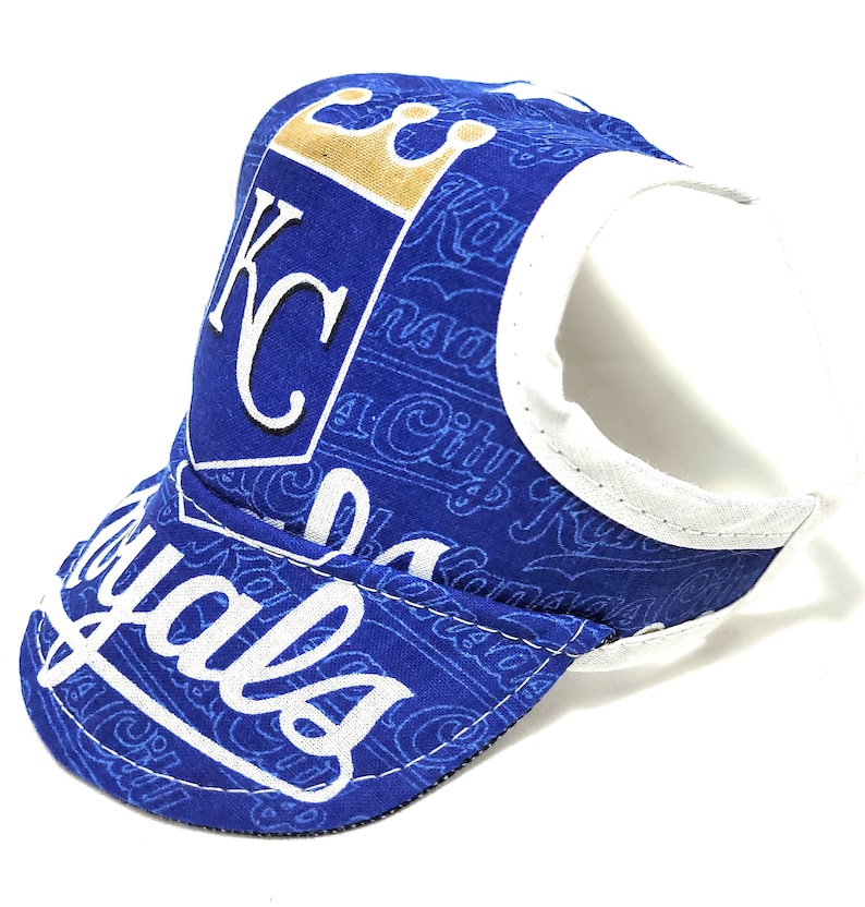 May include: Blue and white baseball cap with a Kansas City Royals logo and a crown. The cap has a white strap and a blue brim.