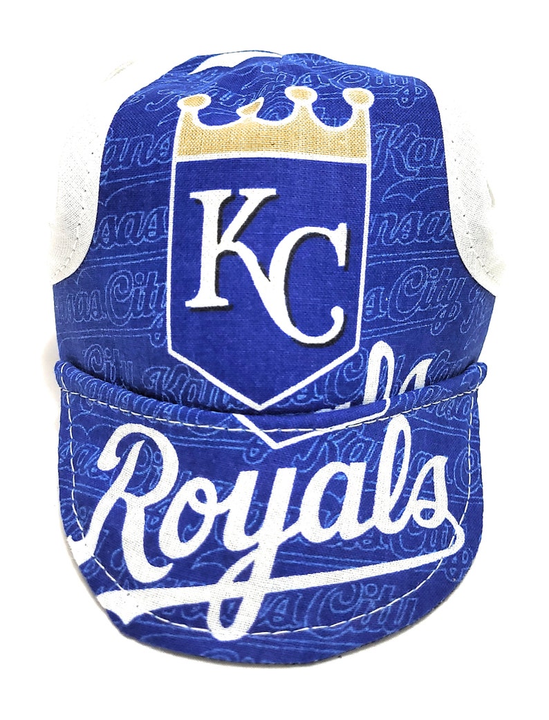 May include: A blue and white cycling cap with a white "Royals" logo and a gold crown above the letters "KC".