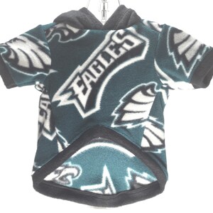 May include: Green, black, and white fleece dog hoodie with the Philadelphia Eagles logo repeated all over. The hoodie has a hood with a black drawstring.