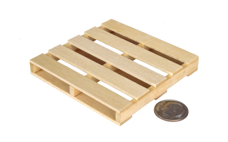K&ouml;nnte beinhalten: Eine kleine Holzpalette, etwa 10 cm breit, aus unbehandeltem hellbraunem Holz. Eine US-Dime wird neben der Palette zur Skalierung gelegt.