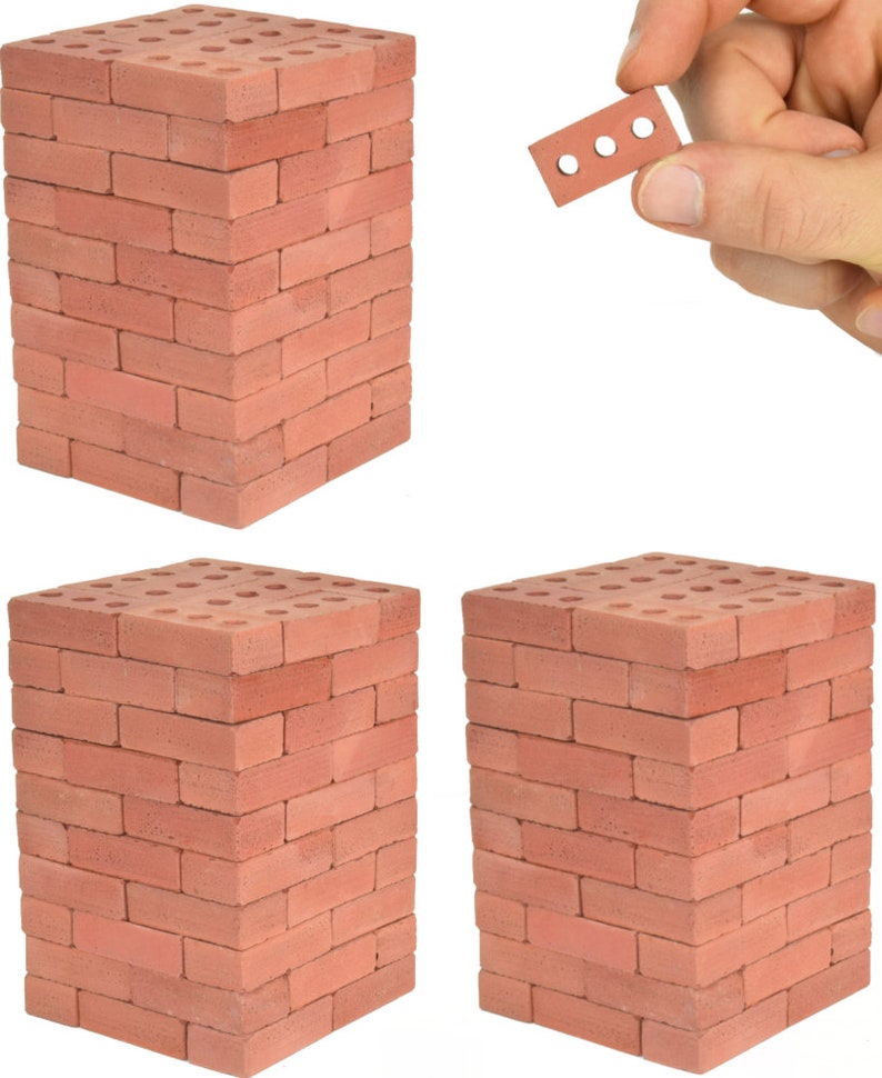 May include: Three stacks of red brick toy blocks, each stack is 10 bricks high. A single brick is held in a hand.