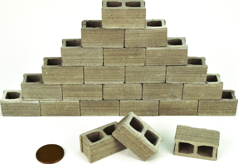 K&ouml;nnte beinhalten: Ein Stapel grauer Betonbl&ouml;cke, die in Pyramidenform angeordnet sind. An der Basis befinden sich vier Bl&ouml;cke, in der n&auml;chsten Reihe drei und so weiter. Die Bl&ouml;cke sind etwa 5 cm hoch und 10 cm breit. Im Vordergrund befindet sich ein Penny als Gr&ouml;&szlig;envergleich.