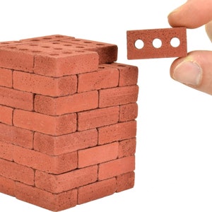 May include: A stack of red brick-shaped foam blocks, with one block being held by a hand. The blocks have a rough texture and are designed to look like real bricks.