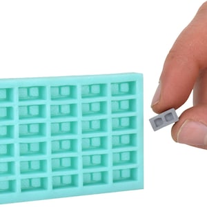 May include: A light blue silicone mold with 30 individual cavities shaped like small concrete blocks. A single gray concrete block is shown next to the mold.