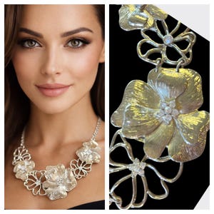May include: Silver-toned floral statement necklace. The necklace features large, textured flower pendants with crystal accents. The design includes openwork details and a delicate chain, creating an elegant and eye-catching accessory.