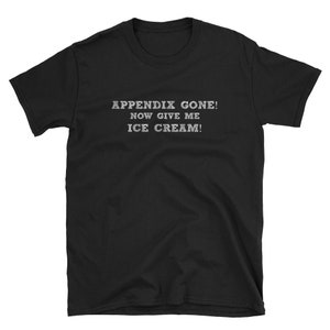 May include: Black t-shirt with the text "APPENDIX GONE! NOW GIVE ME ICE CREAM!" in a white, slightly distressed font. The shirt is a short-sleeved crew neck style.
