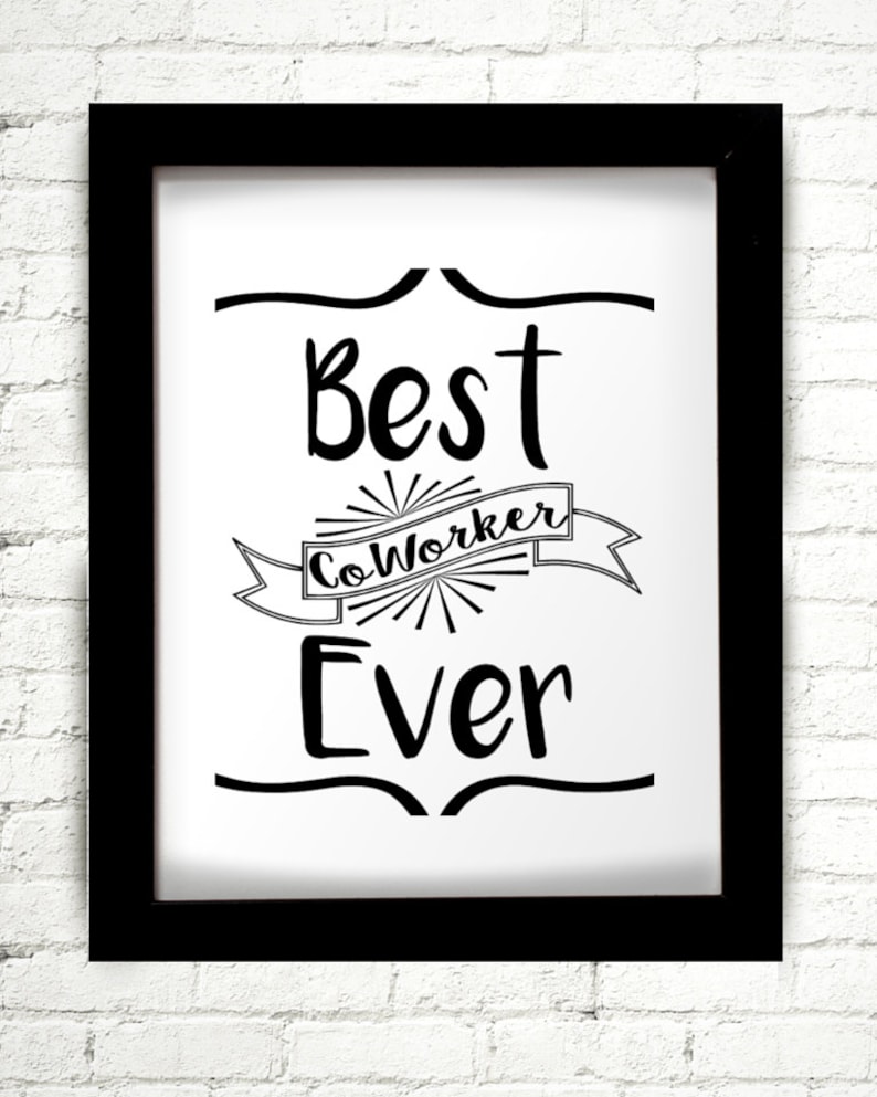 May include: A framed print with the words "Best CoWorker Ever" in black script. The text is centered on a white background, with decorative lines above and below the text. The frame is black, and the background is a white brick wall.