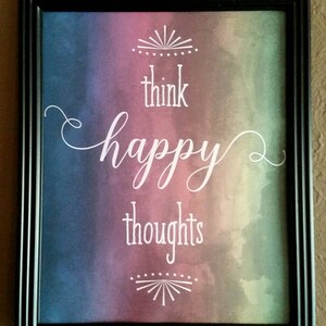 K&ouml;nnte beinhalten: Ein gerahmter Druck mit einem Aquarellhintergrund in Blaut&ouml;nen, Lila und Gr&uuml;n. Der Text "think happy thoughts" ist in wei&szlig;er Kursivschrift geschrieben.