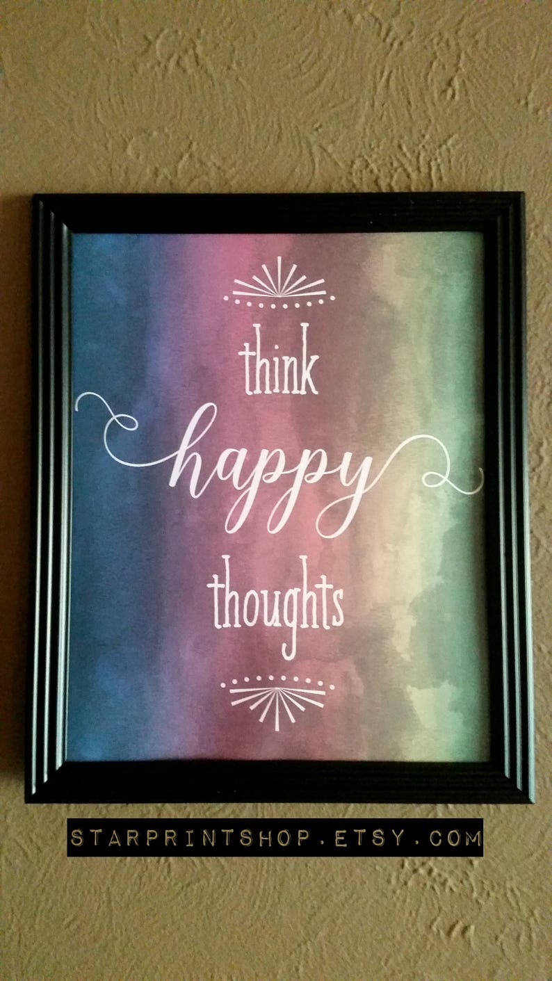 K&ouml;nnte beinhalten: Ein gerahmter Druck mit einem Aquarellhintergrund in Blaut&ouml;nen, Lila und Gr&uuml;n. Der Text "think happy thoughts" ist in wei&szlig;er Kursivschrift geschrieben.