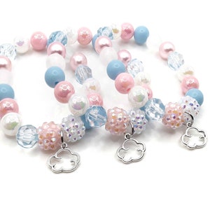 May include: Three beaded bracelets in pastel colors. The bracelets feature a mix of pink, blue, white, and iridescent beads. Each bracelet has a silver cloud charm. The beads vary in size and texture, including round, faceted, and textured beads.