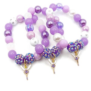 May include: Three purple, white, and iridescent beaded bracelets with fairy charms. Each bracelet has a different pattern of beads.