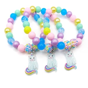 May include: Three colorful beaded bracelets with unicorn cat charms. The bracelets are made with pastel pink, purple, blue, green, and yellow beads.