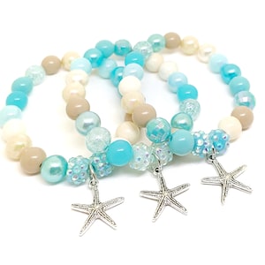 May include: Three beaded bracelets with blue, white, and beige beads and silver starfish charms.