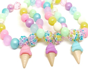 May include: Three pastel-colored beaded bracelets with ice cream cone charms. The bracelets are made with light blue, pink, yellow, and purple beads.