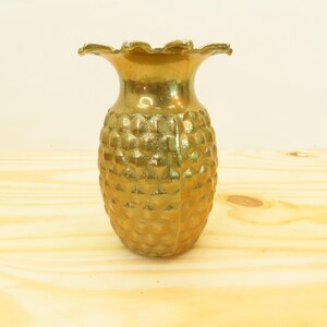 May include: A gold pineapple-shaped vase with a textured surface.