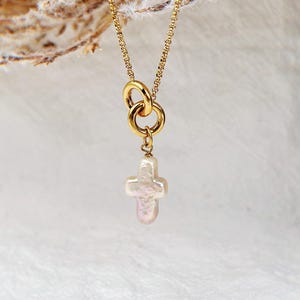 Op de afbeelding: Een gouden ketting met een dubbele ring hanger en een parel kruis bedel.