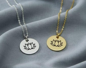 May include: Two necklaces with circular pendants featuring a lotus flower design. One necklace has a silver chain and pendant, the other has a gold chain and pendant. The pendants are approximately 1 inch in diameter.